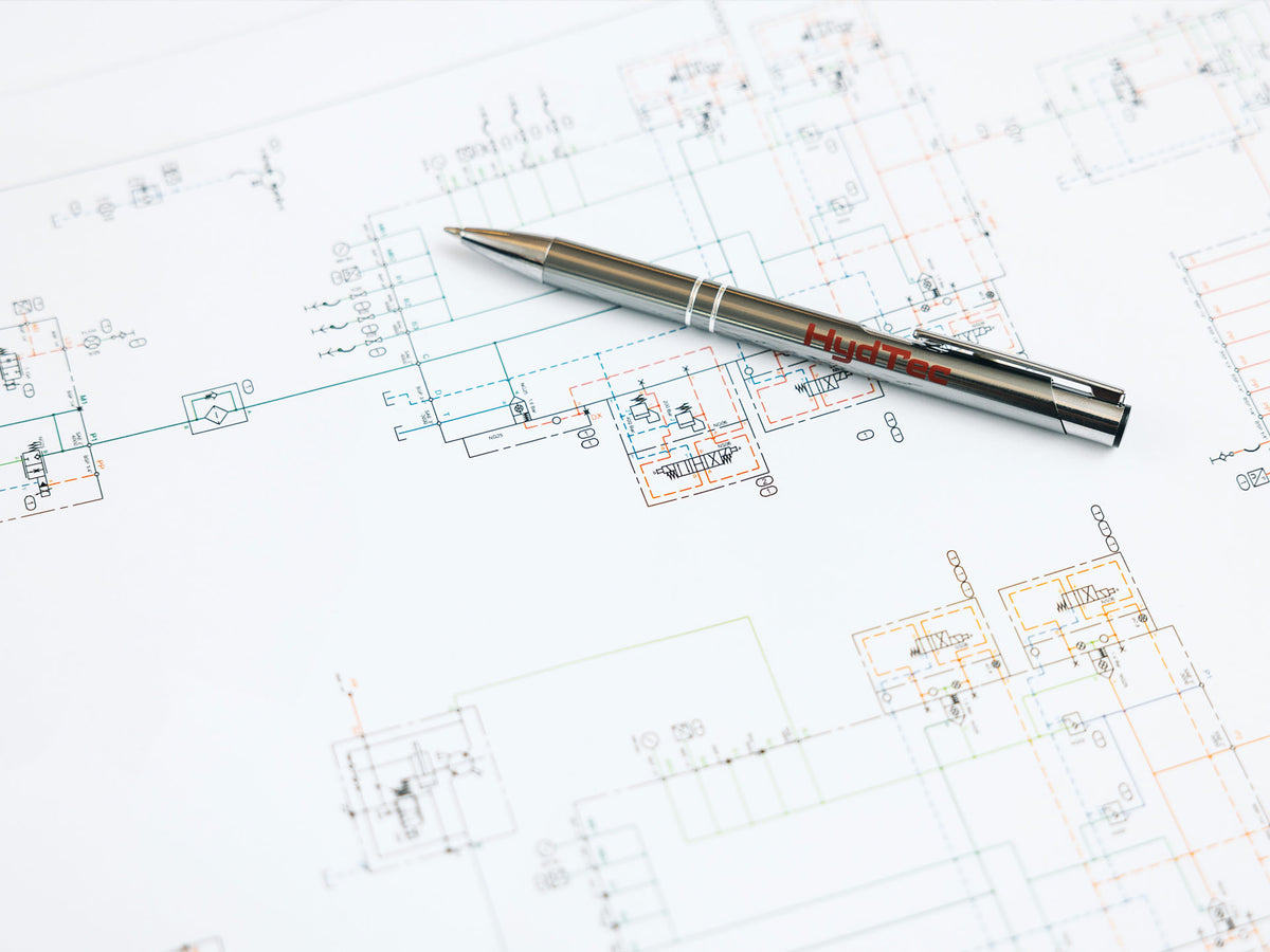 Silver "HydTec" branded pen resting on a printed hydraulic circuit schematic.